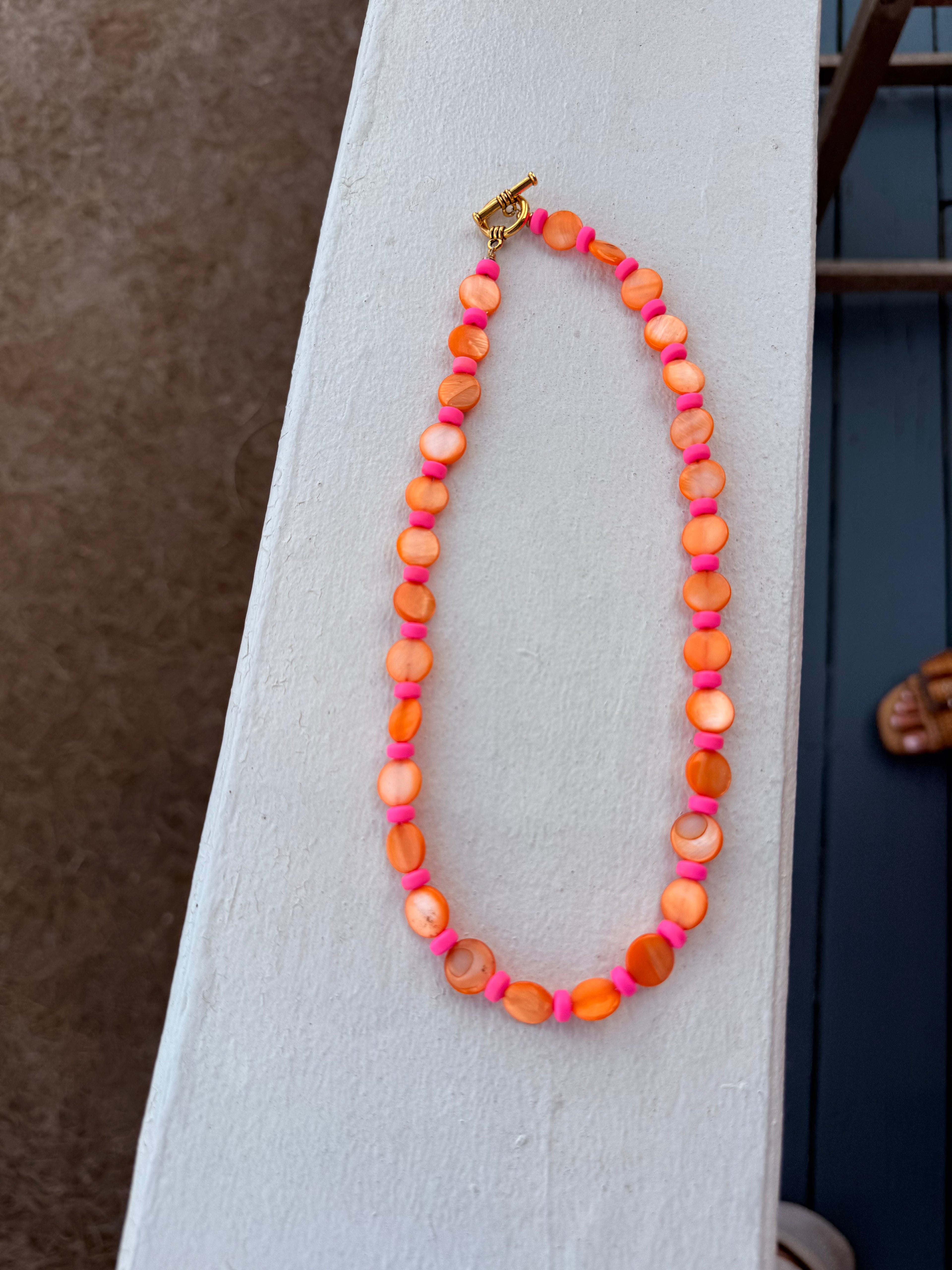Necklace with orange and pink beads on a white surface